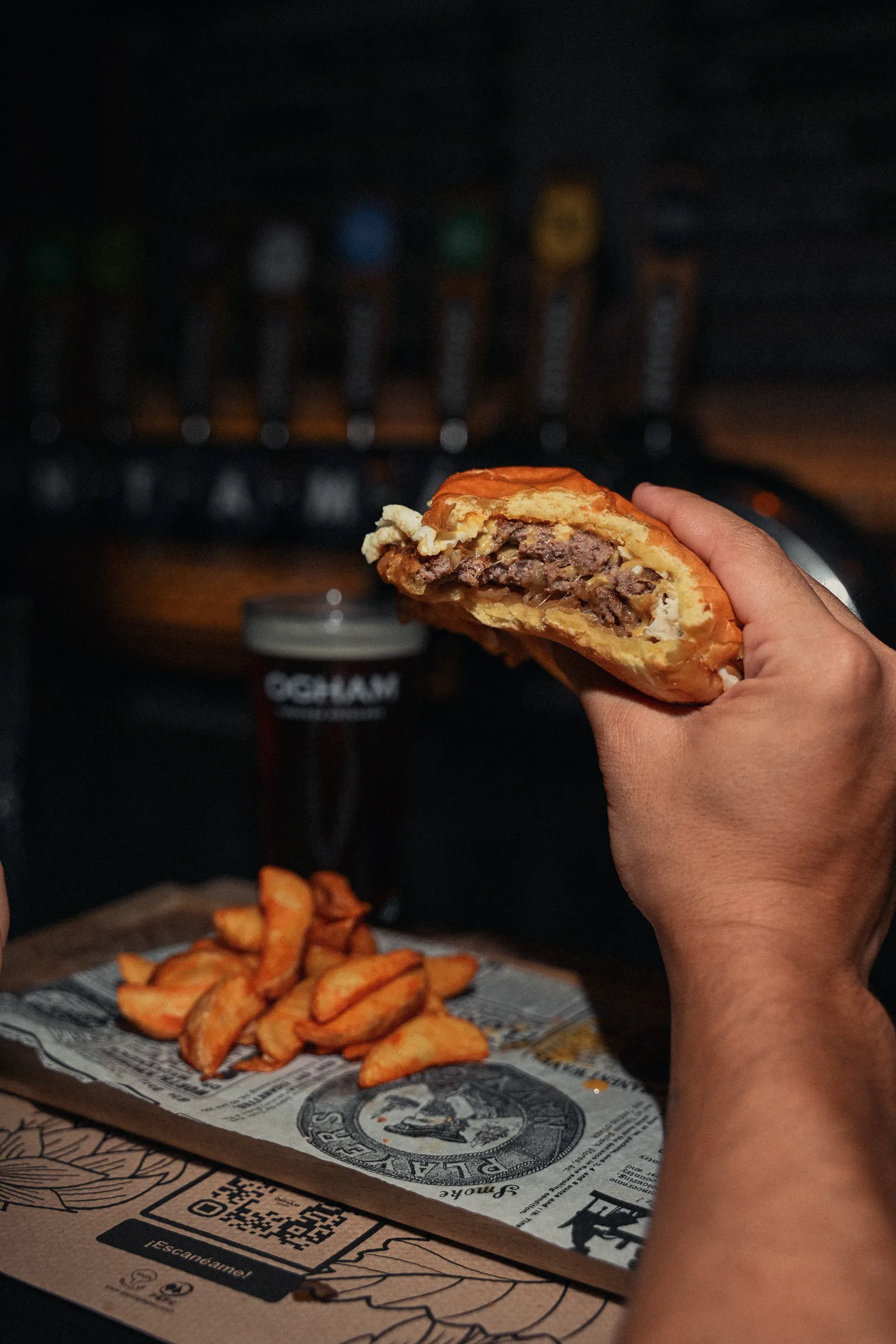 An OGHAM burger held in one hand, straight from the kitchen