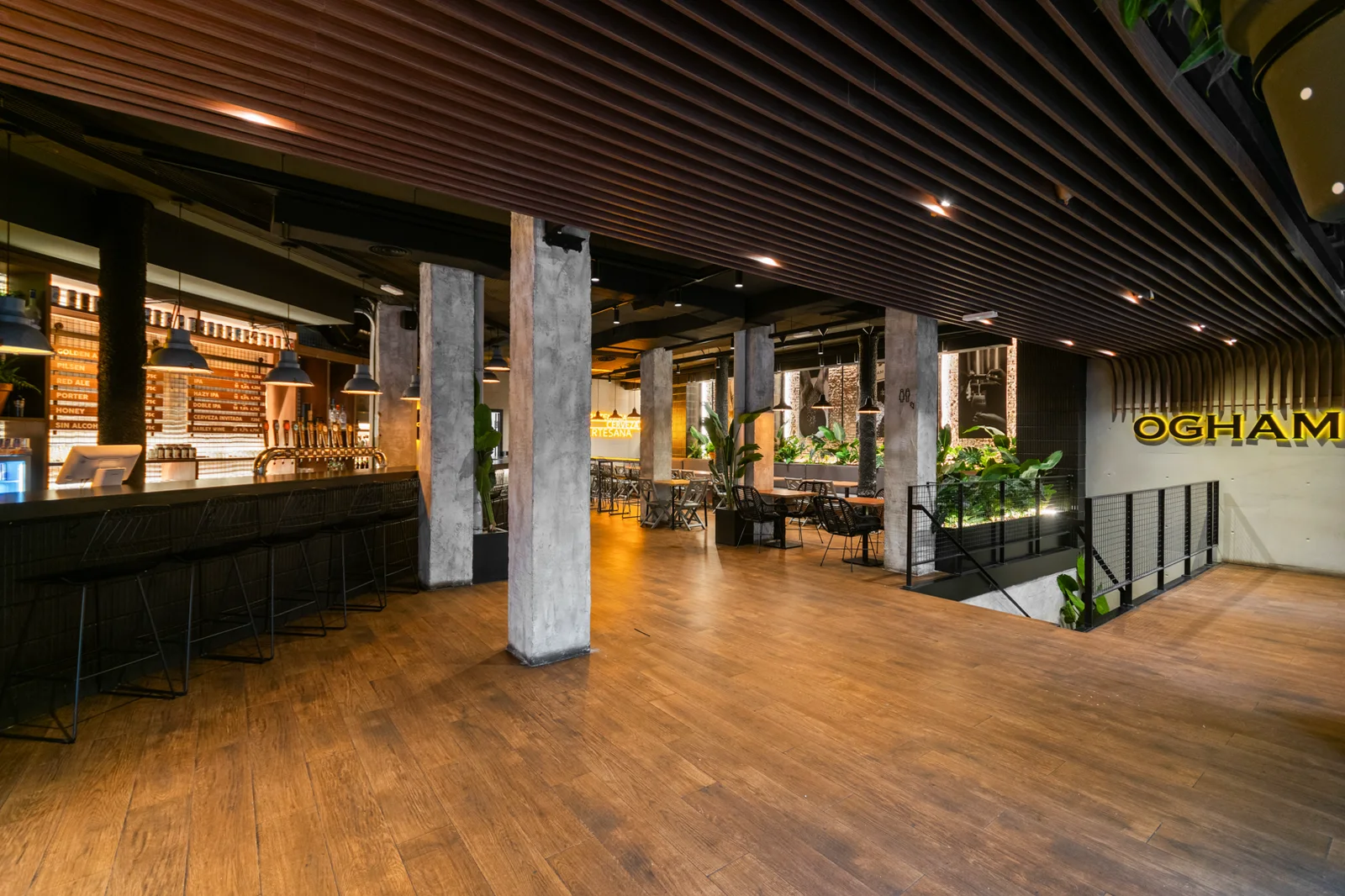 La sala de OGHAM en Gran Via: la barra al fondo, mesas altas y columnas de hormigón